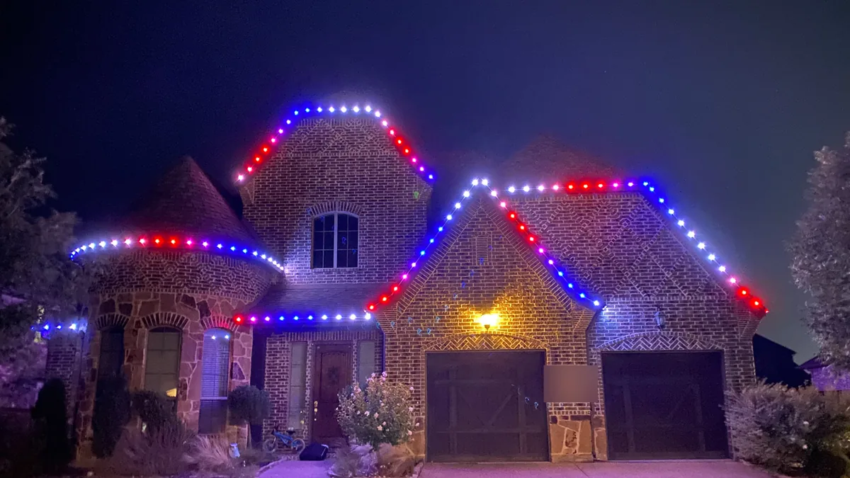 Blue Hopper permanent red, white and blue roofline lighting on a brick home