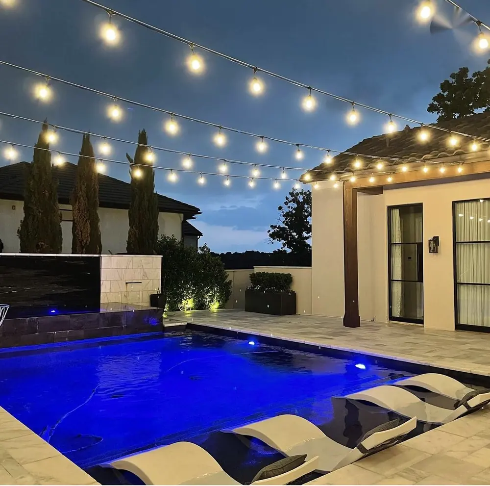 Bistro lighting with warm string lights over a blue pool