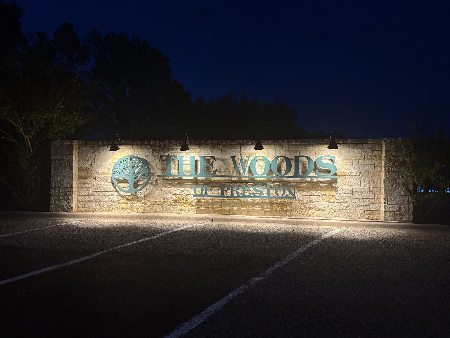 Commercial lighting across the stone monument sign for The Woods of Preston