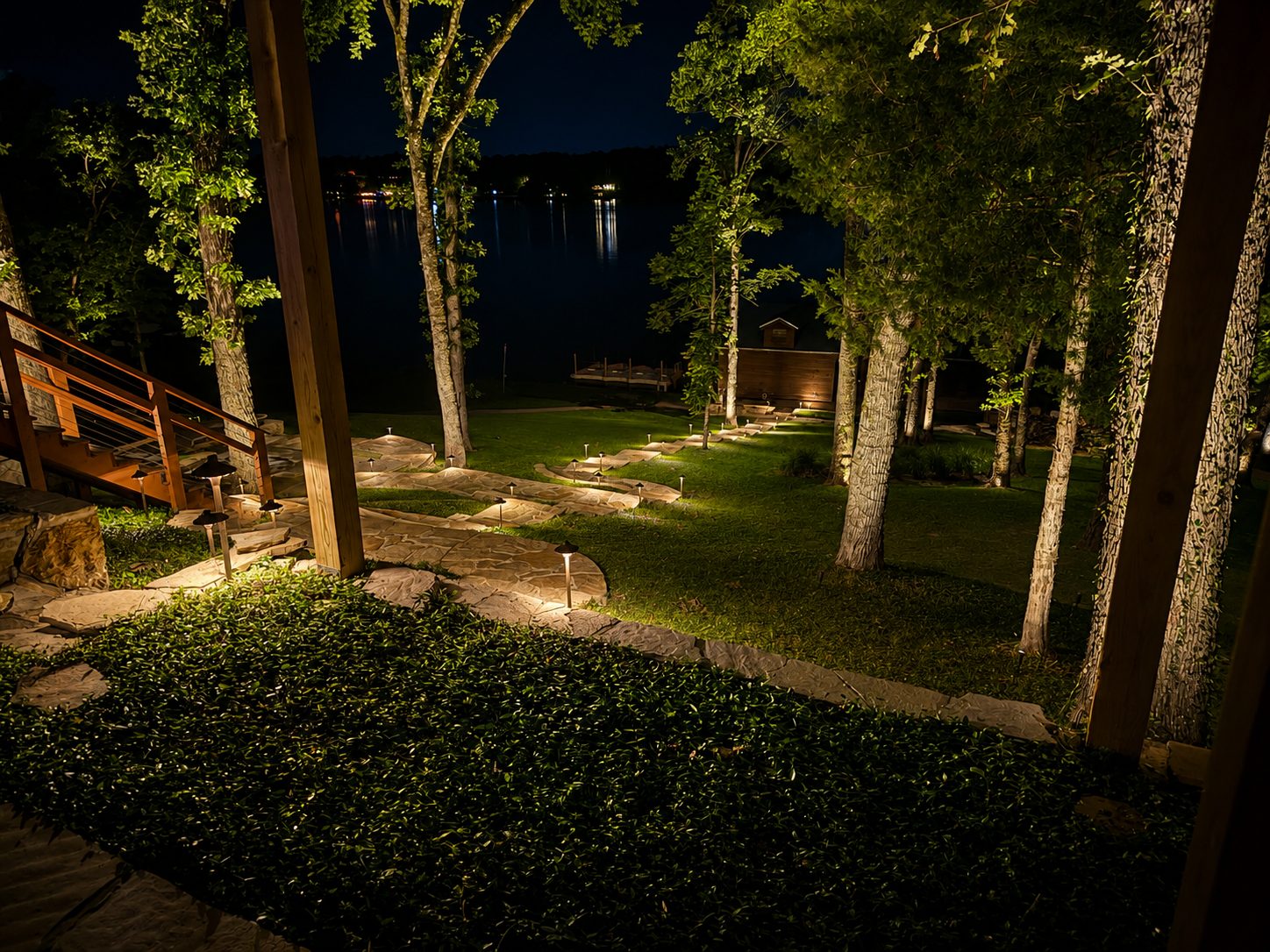 Stone path lights toward a lake and dock