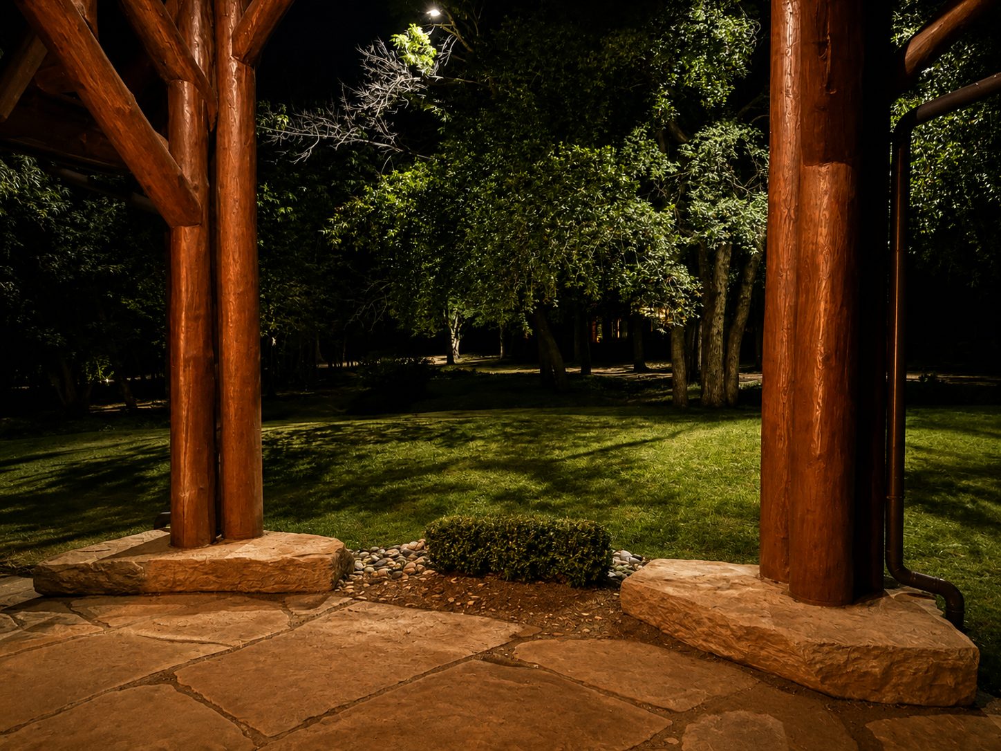 Moon lighting with tree shadows on the ground beyond a timber pavilion