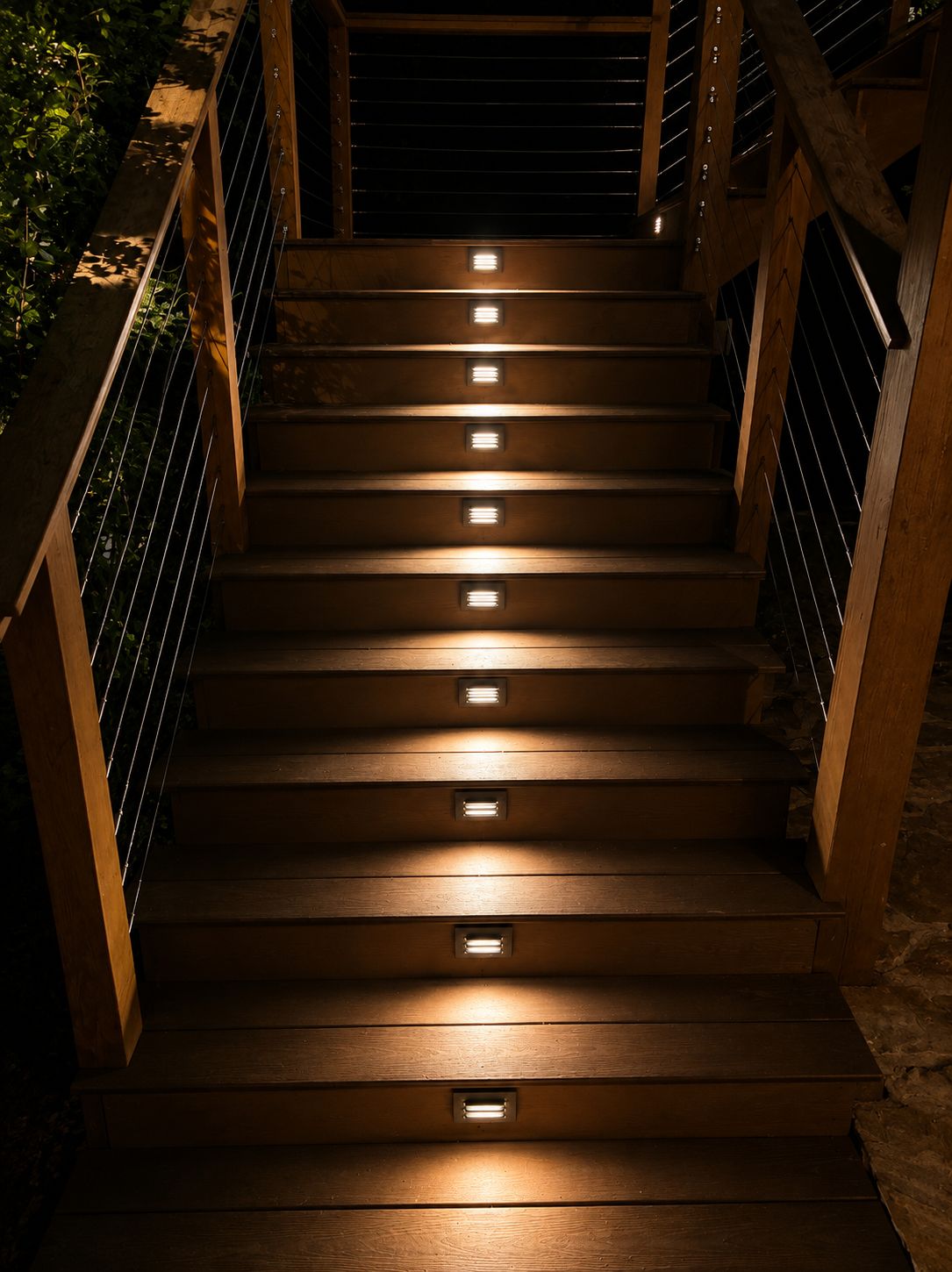 Wood steps with recessed tread lights and a dark metal rail